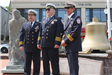 3 men in uniform pose for picture in front of a memorial