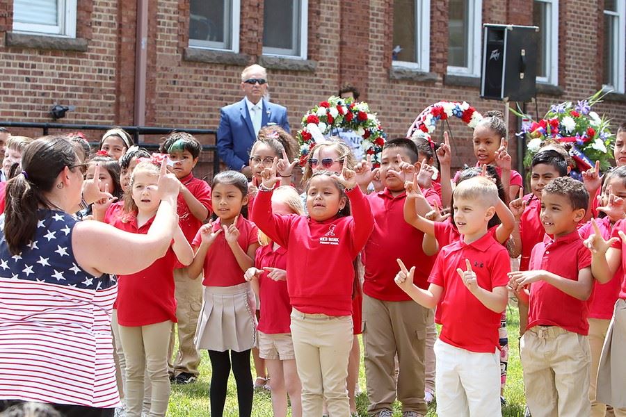 Kids in red performing at the Memorial Day Service with their instructor leading them